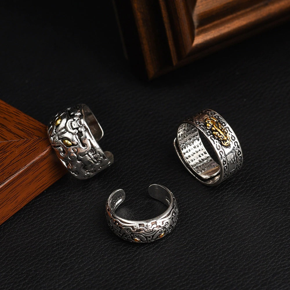 Drei silberne Ringe mit goldenen Verzierungen auf schwarzem Hintergrund, Schmuckdesign.